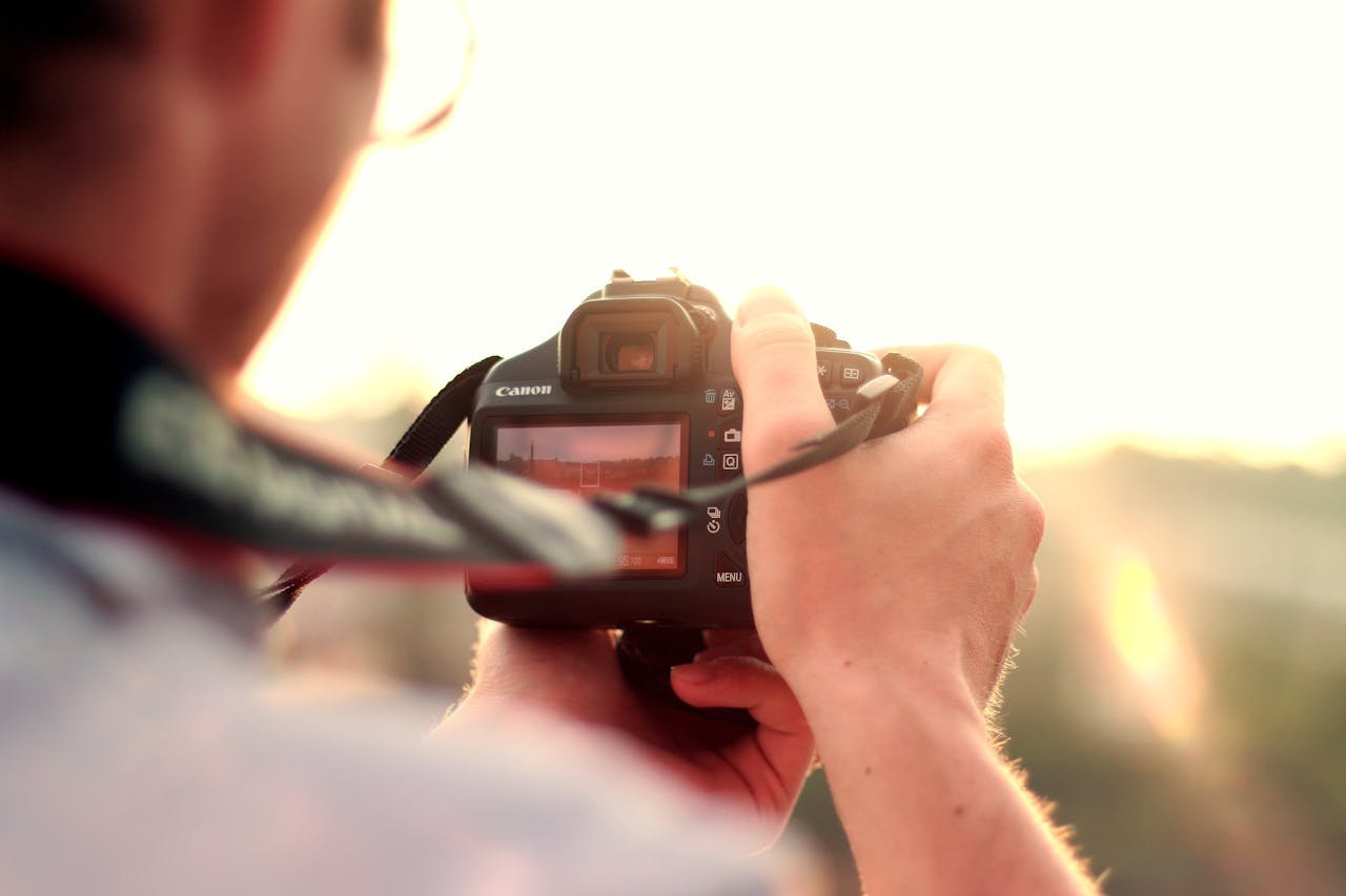 Man Holding Black Dslr Camera Standing in Front of the Sun